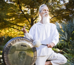mehtab holding a gong in tree pose in the sunlight