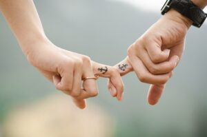 couple with hooked index fingers and the same tattoo